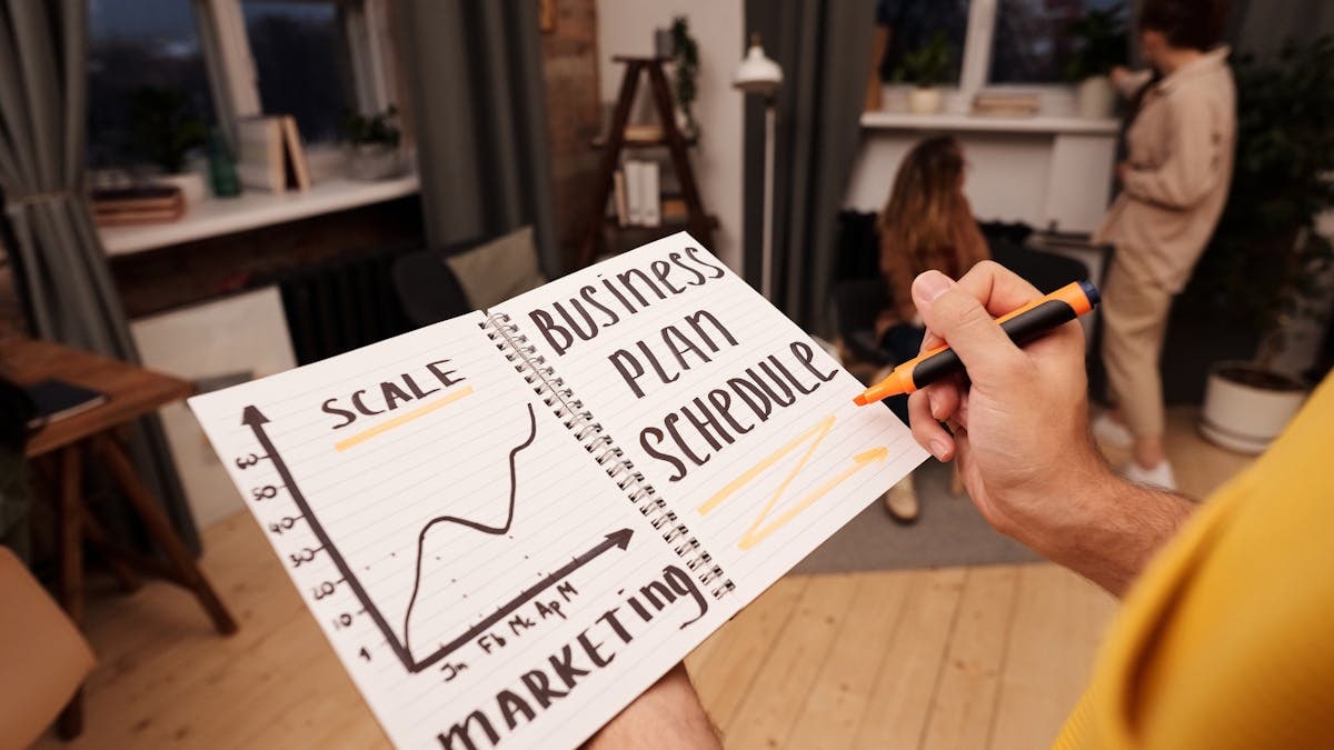 Person holding a notebook with planning details and graph for business strategy indoors.